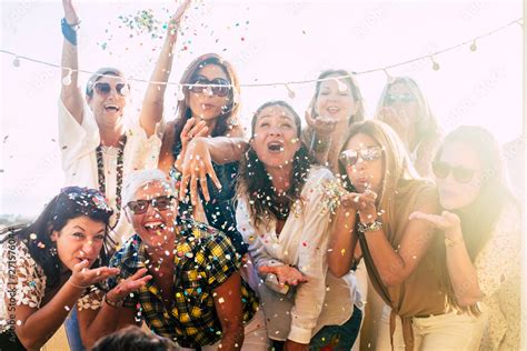 Group Of People Celebrate Together Having A Lot Of Fun Blowing Coloured Confetti Friendship