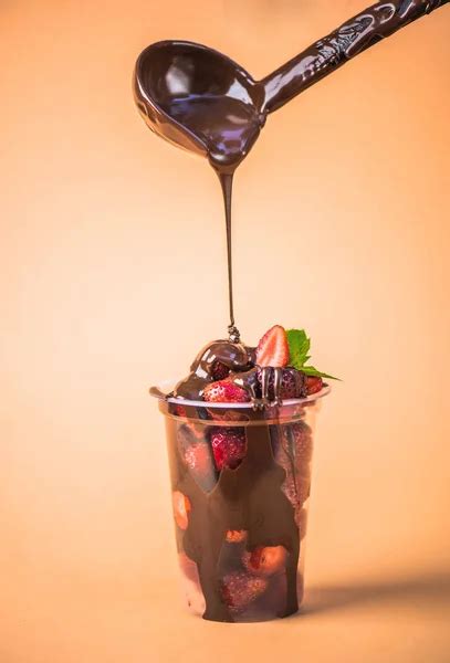 Pouring Fresh Strawberries In Plastic Cup With Melted Chocolate On Pouring Fresh Strawberries In Plastic Cup With Melted Chocolate On